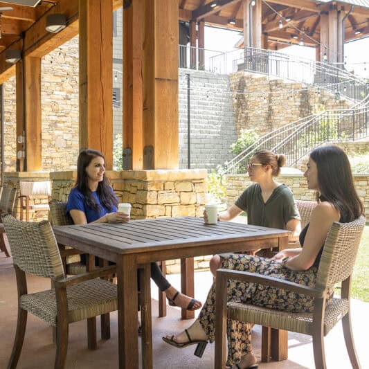 Three women sit at a table on the outside Patio of SmoothRock Cafe